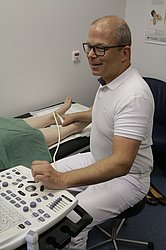 Dr. med. Feldmann untersucht einen Fuß mit Ultraschall